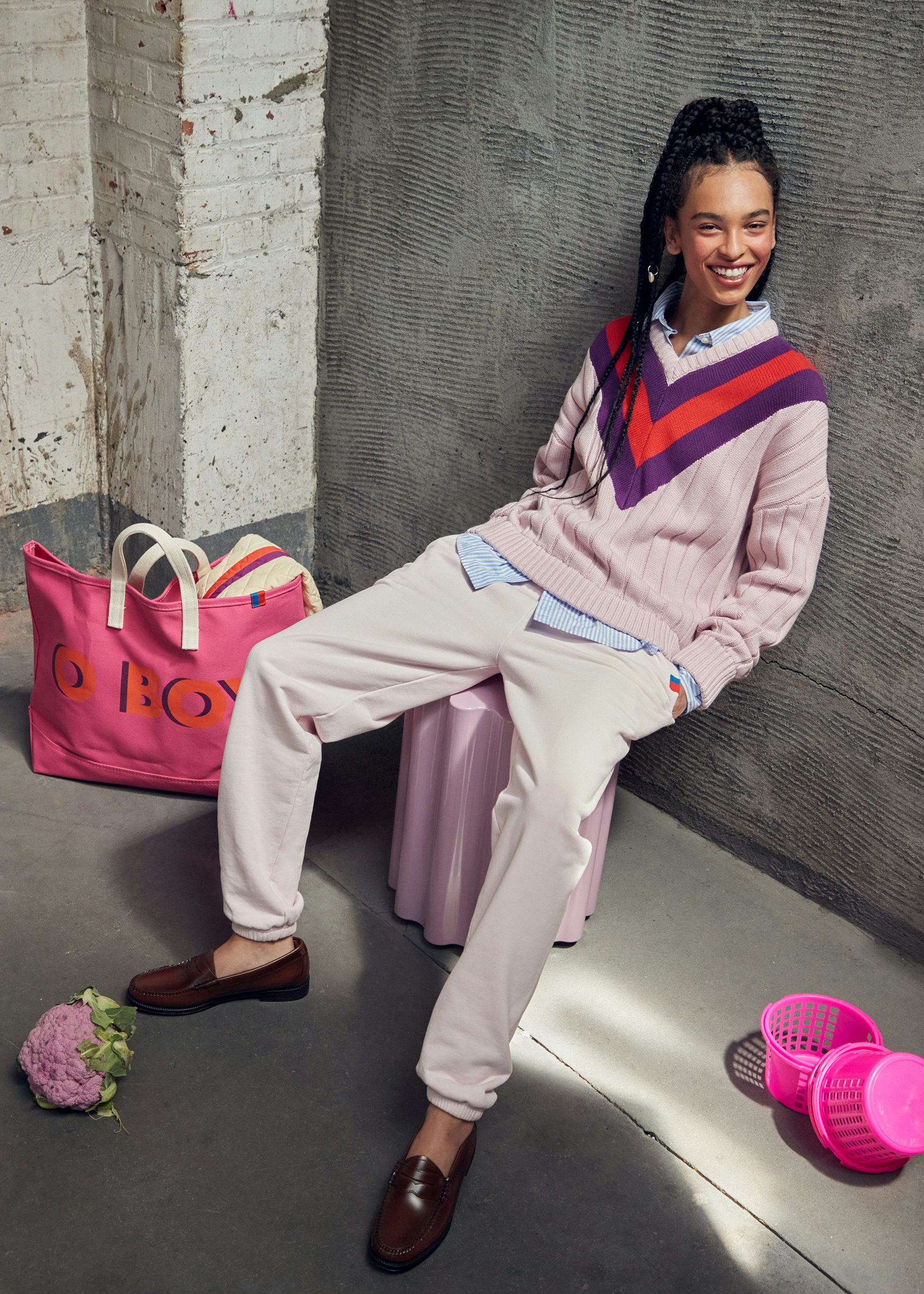 Model wearing the new light link and plum fall collection. She is wearing the new Yale v-neck sweater in light pink with a plum and poppy stripe collar. She paired it with the new light pink sweatpants. She also has the new O BOY pink/poppy tote.